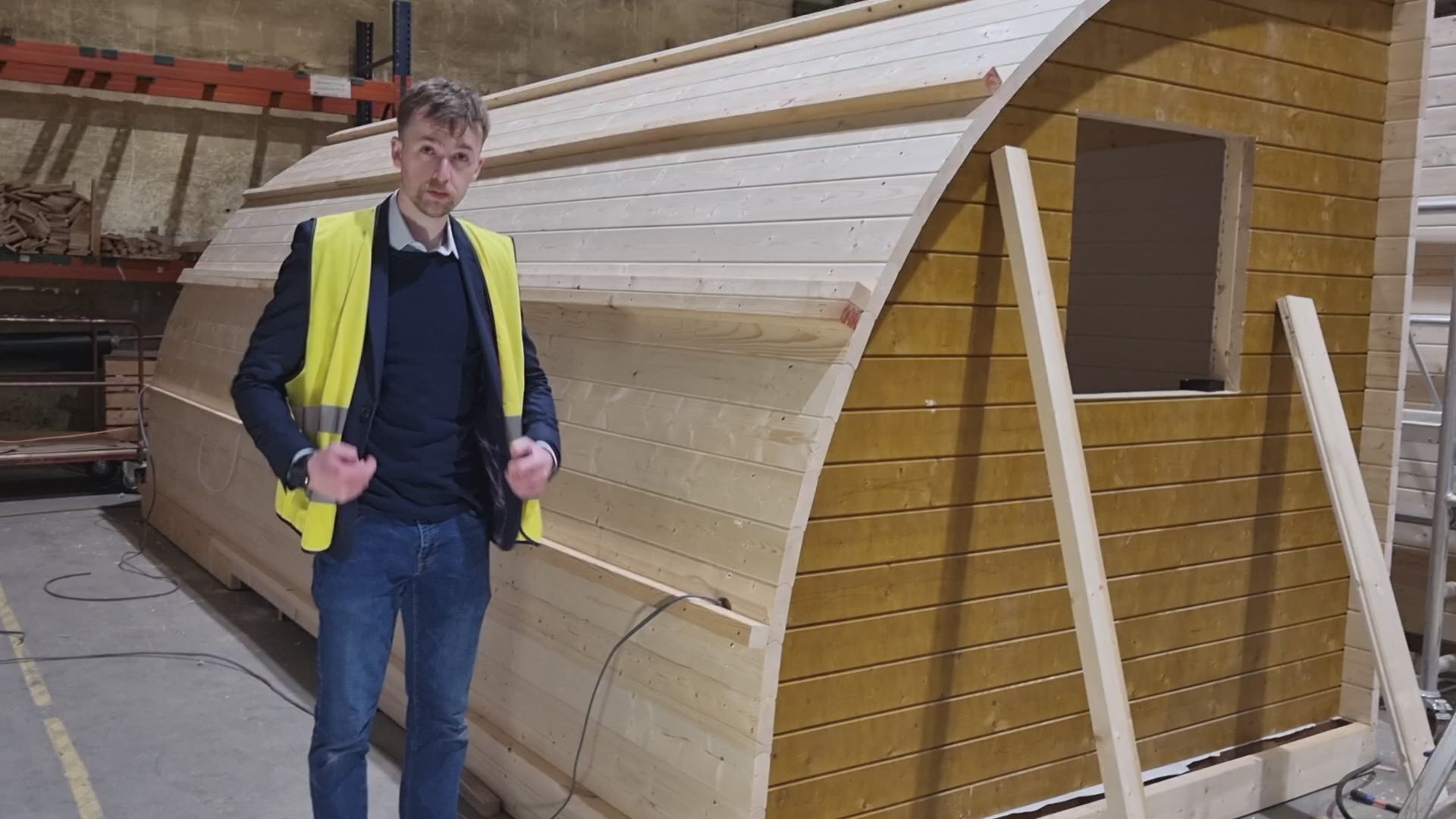 Taylor Glass inside the Lithuanian factory where GlampLaunch pods are built, explaining pod features and the factory-direct pricing model that sets the company apart.