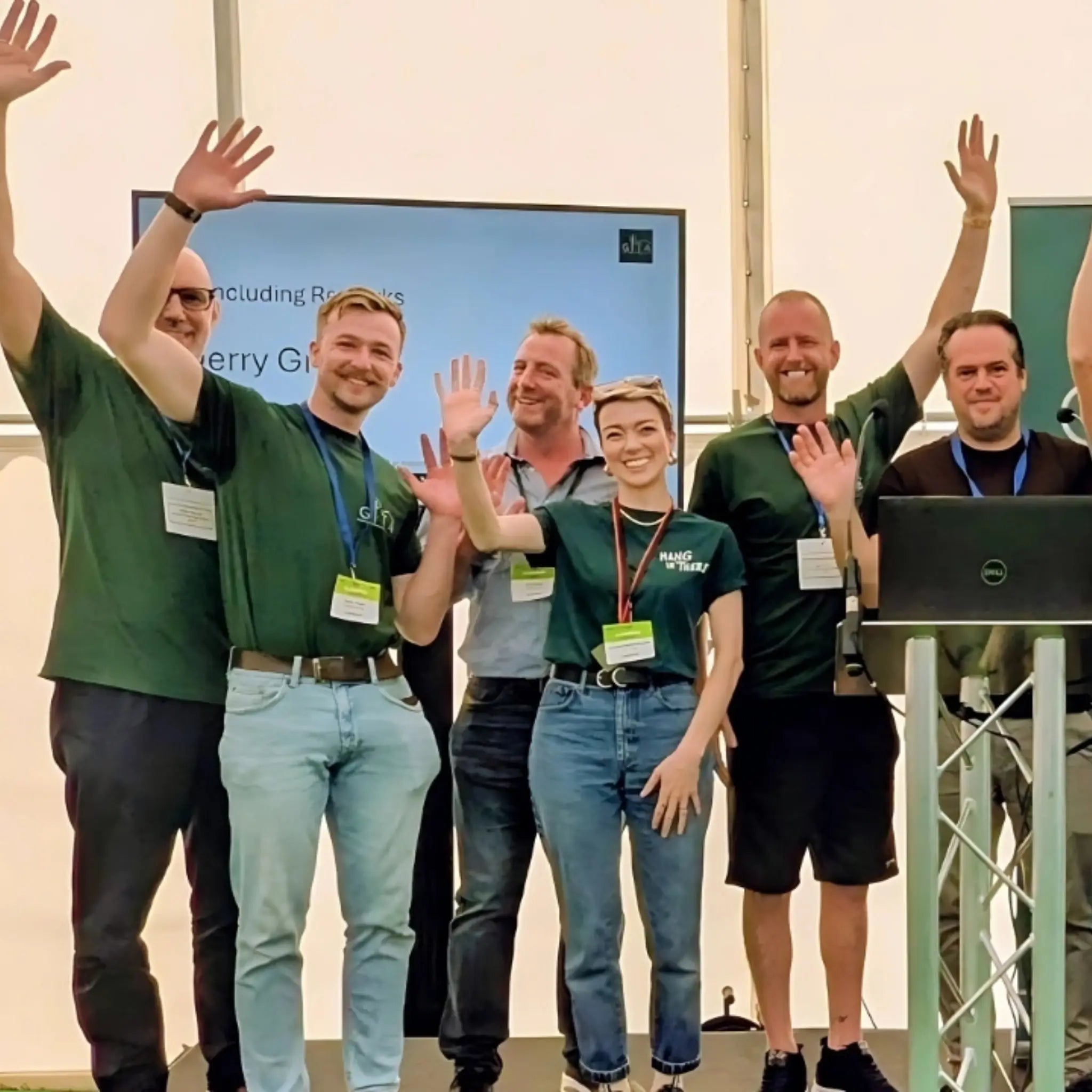 GITA members and directors standing together on stage at the Annual General Meeting, raising hands in celebration at The Glamping Show UK 2025.