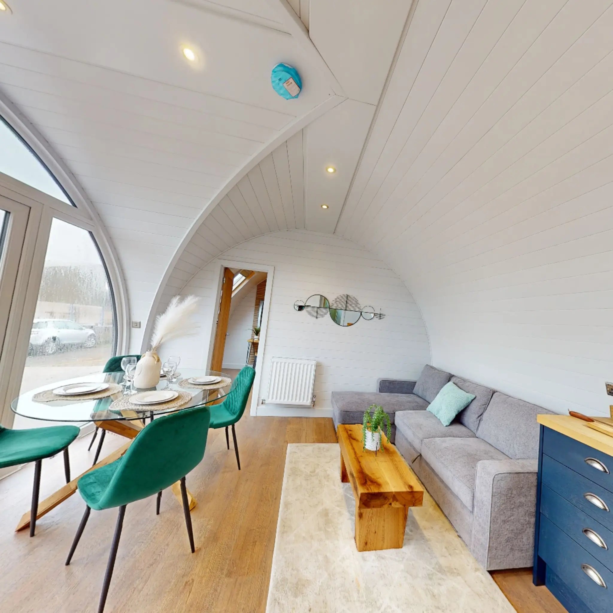 Luxury glamping pod interior with arched ceiling, dining area, sofa, and modern décor