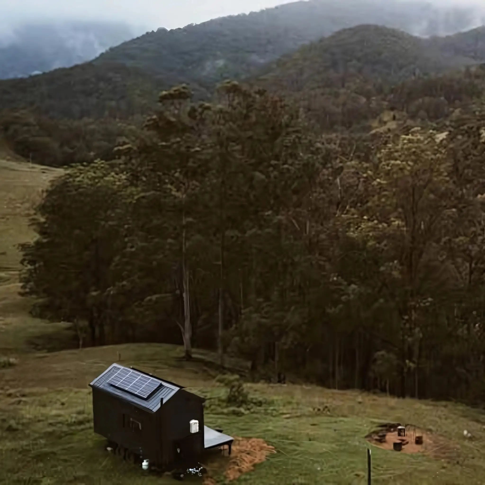 Remote off-grid cabin with solar panels in front of woodland, showcasing eco-friendly energy solutions.