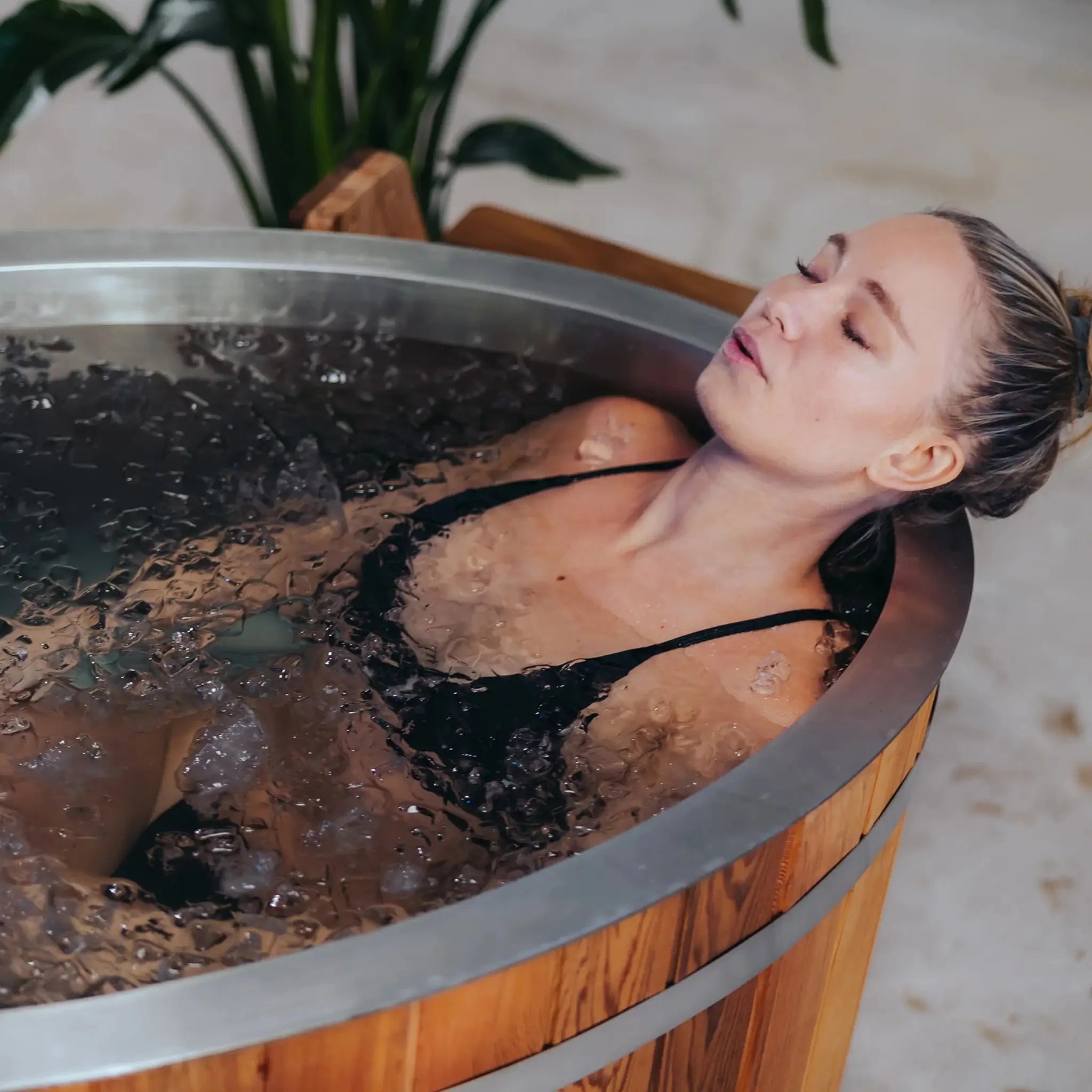 Woman soaking in a cold plunge tub, demonstrating wellness, recovery, and stress relief benefits for glamping guests.