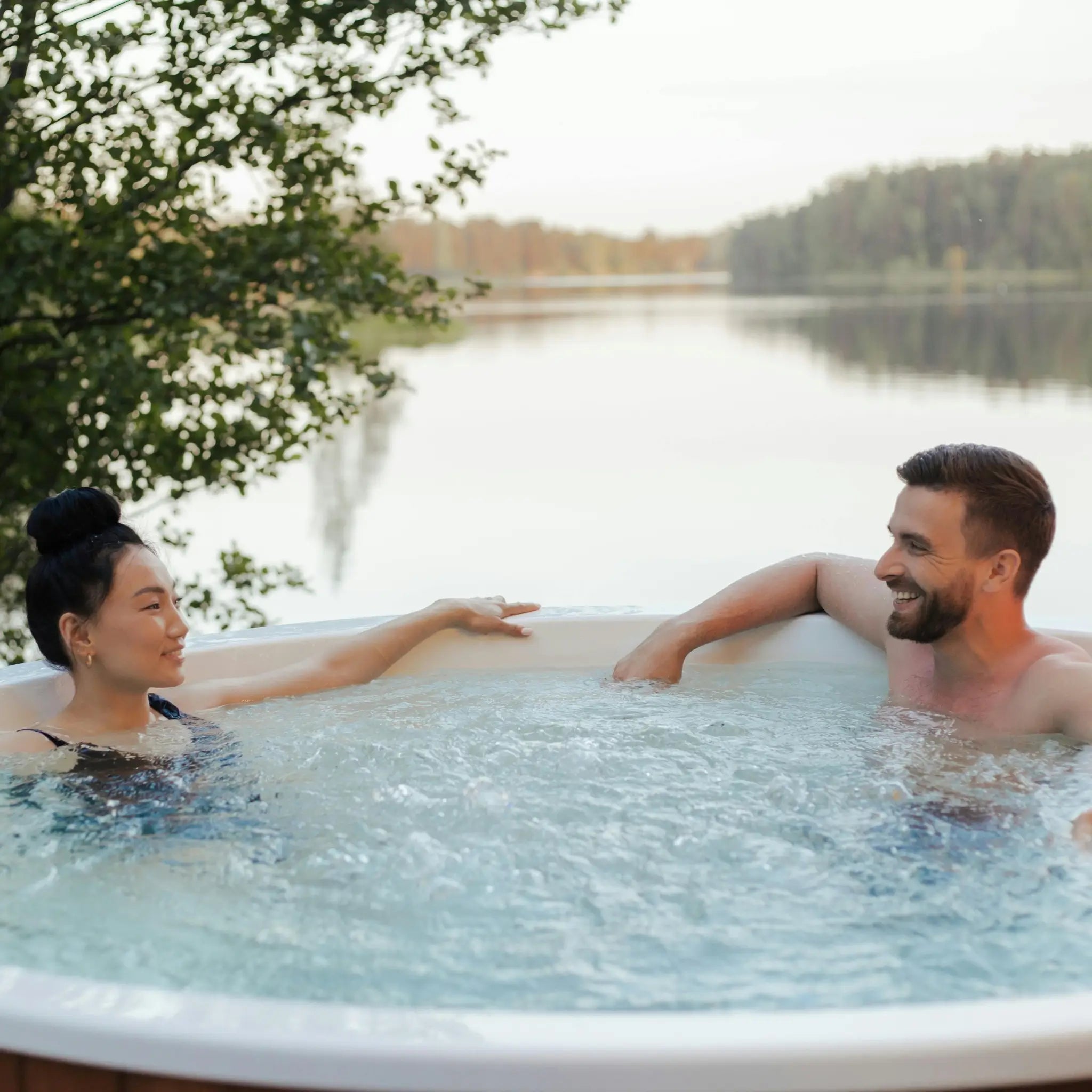 Couple relaxing in a private outdoor hot tub at a glamping site, showcasing luxury wellness experiences and romantic stays.