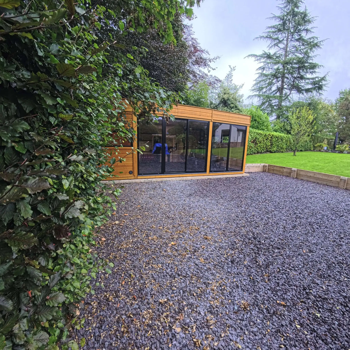 Outdoor sauna and gym building with modern glazed frontage overlooking a landscaped garden