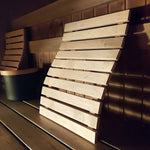 Wooden sauna bench backrest in use inside a sauna with warm lighting and timber bench seating