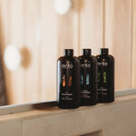 Rento sauna scent bottles displayed on a sauna bench with warm timber interior in the background.