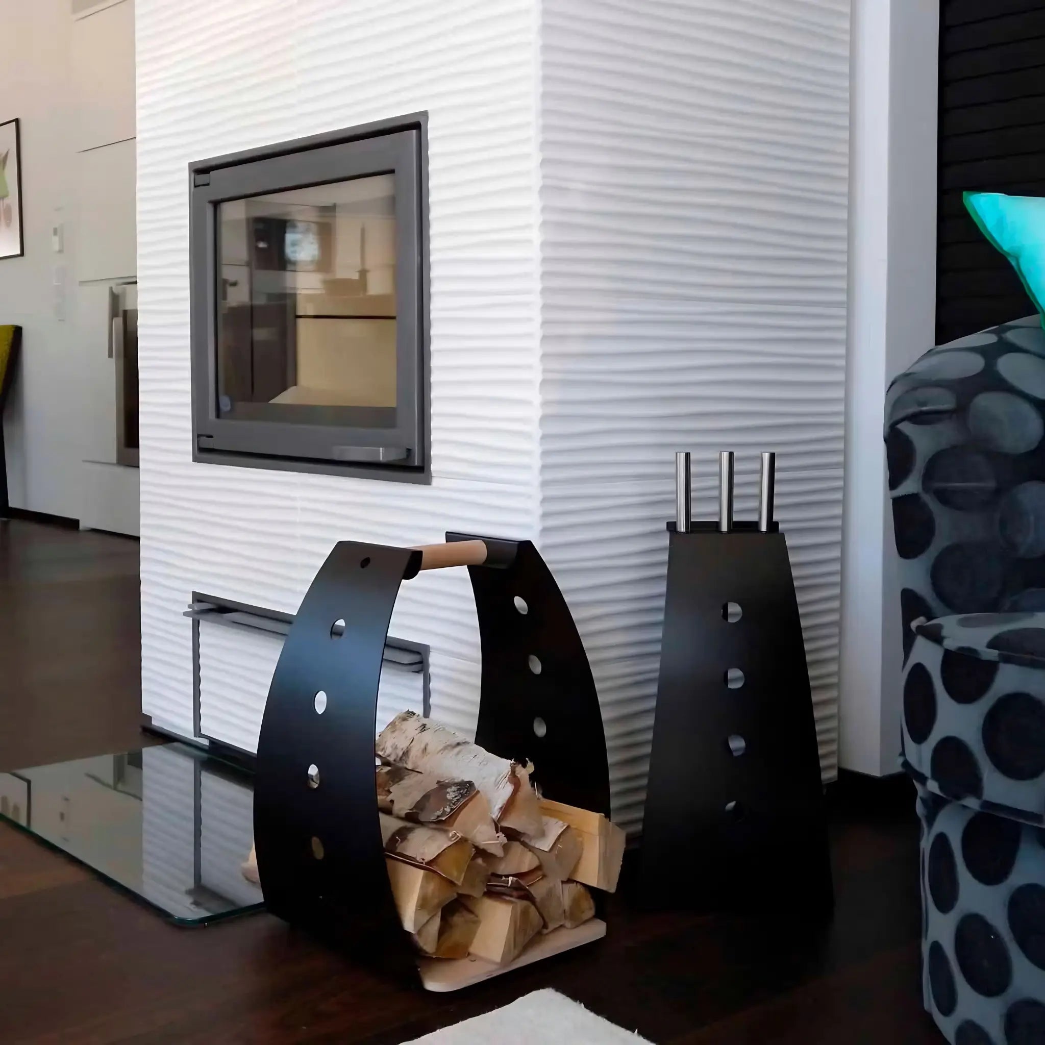 Black and white fireplace tool kits styled beside a white textured fireplace with a black log carrier filled with firewood.