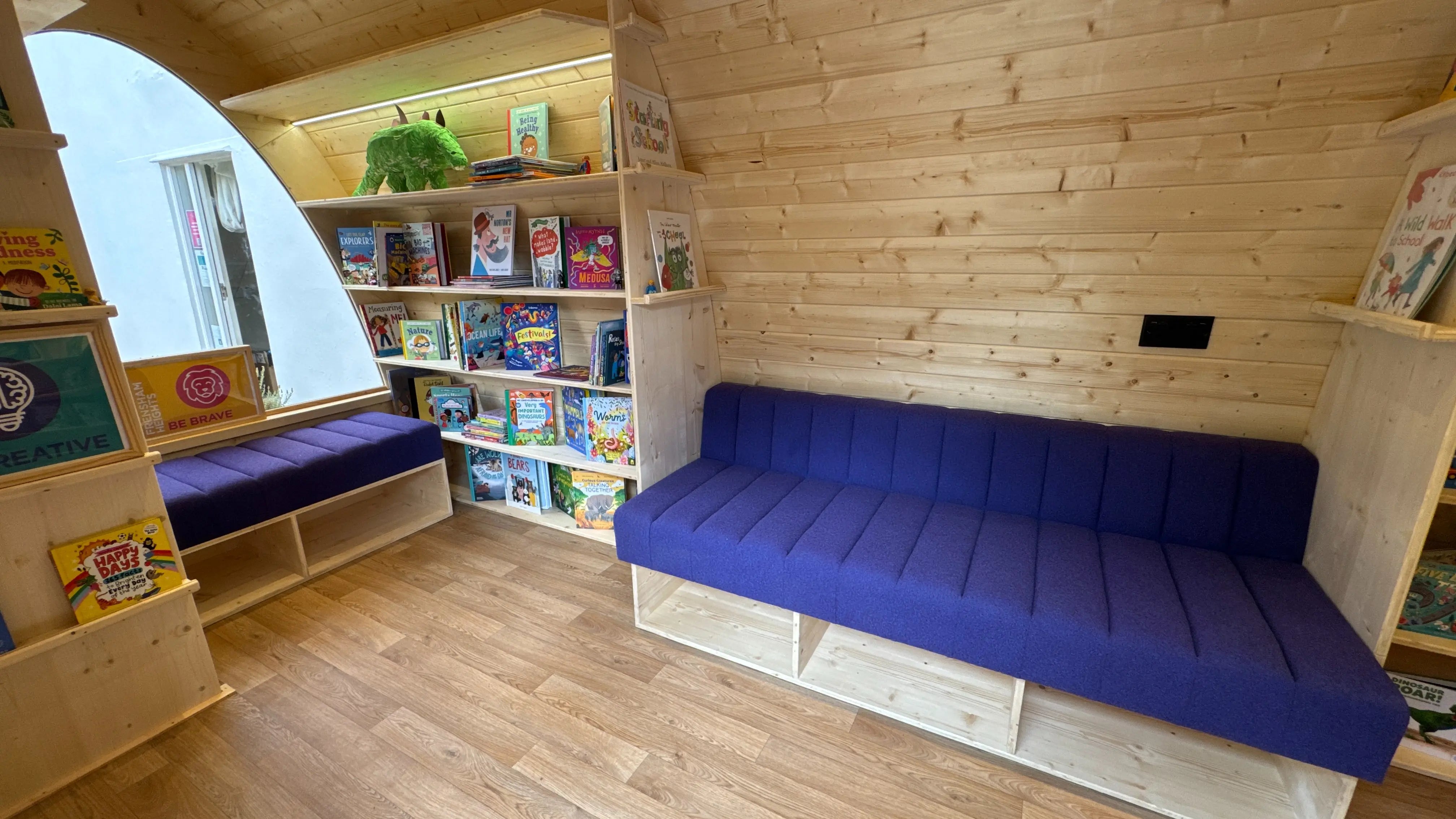 Interior of Frensham Heights library pod with bookshelves, seating, and natural wood design for students.