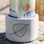 Hukka Saunaviilee soapstone drink cooler holding a can, shown close up with natural leaf engraving.