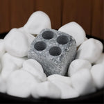 Hukka soapstone steamstone placed among white sauna stones for gentle steam and humidity
