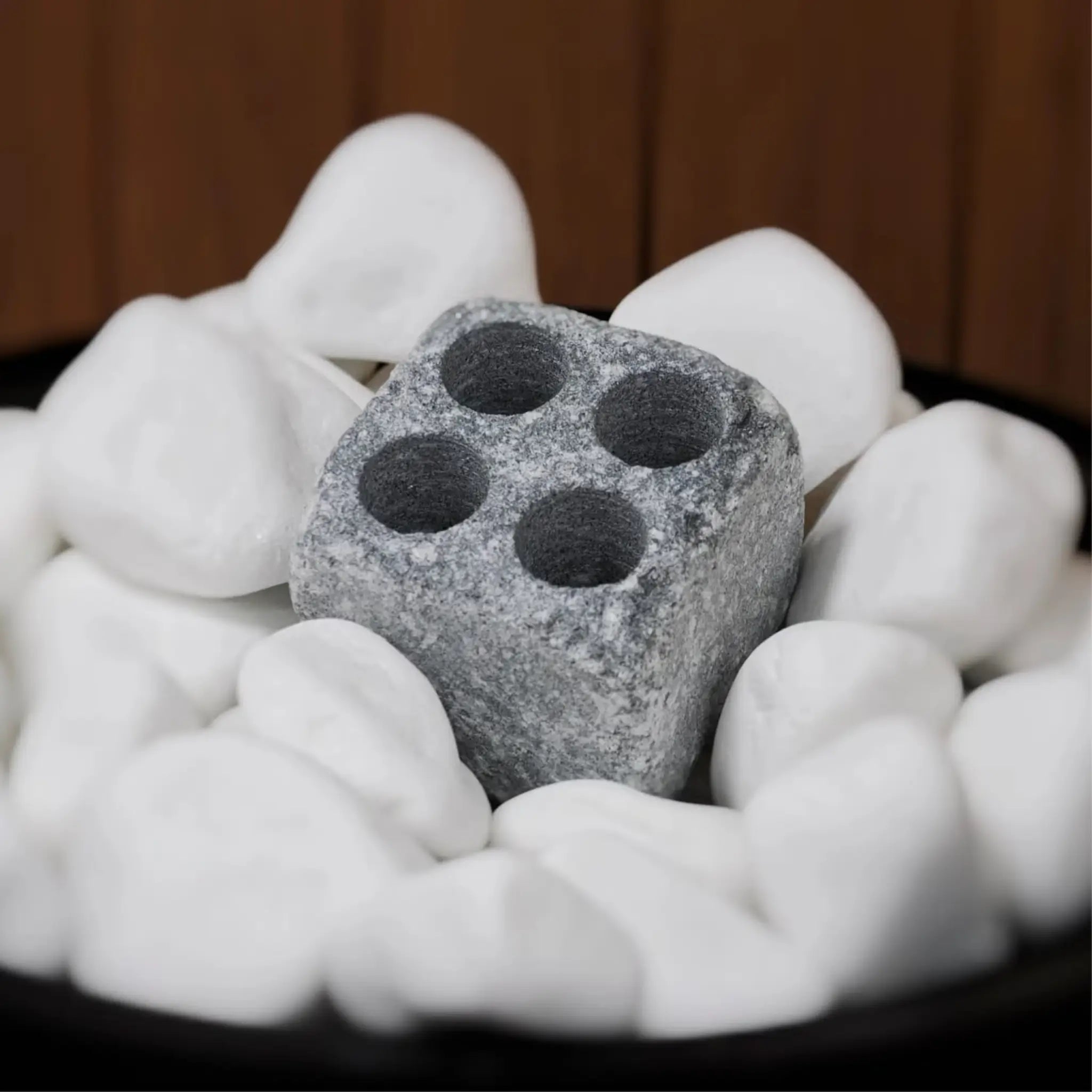 Hukka soapstone steamstone placed among white sauna stones for gentle steam and humidity