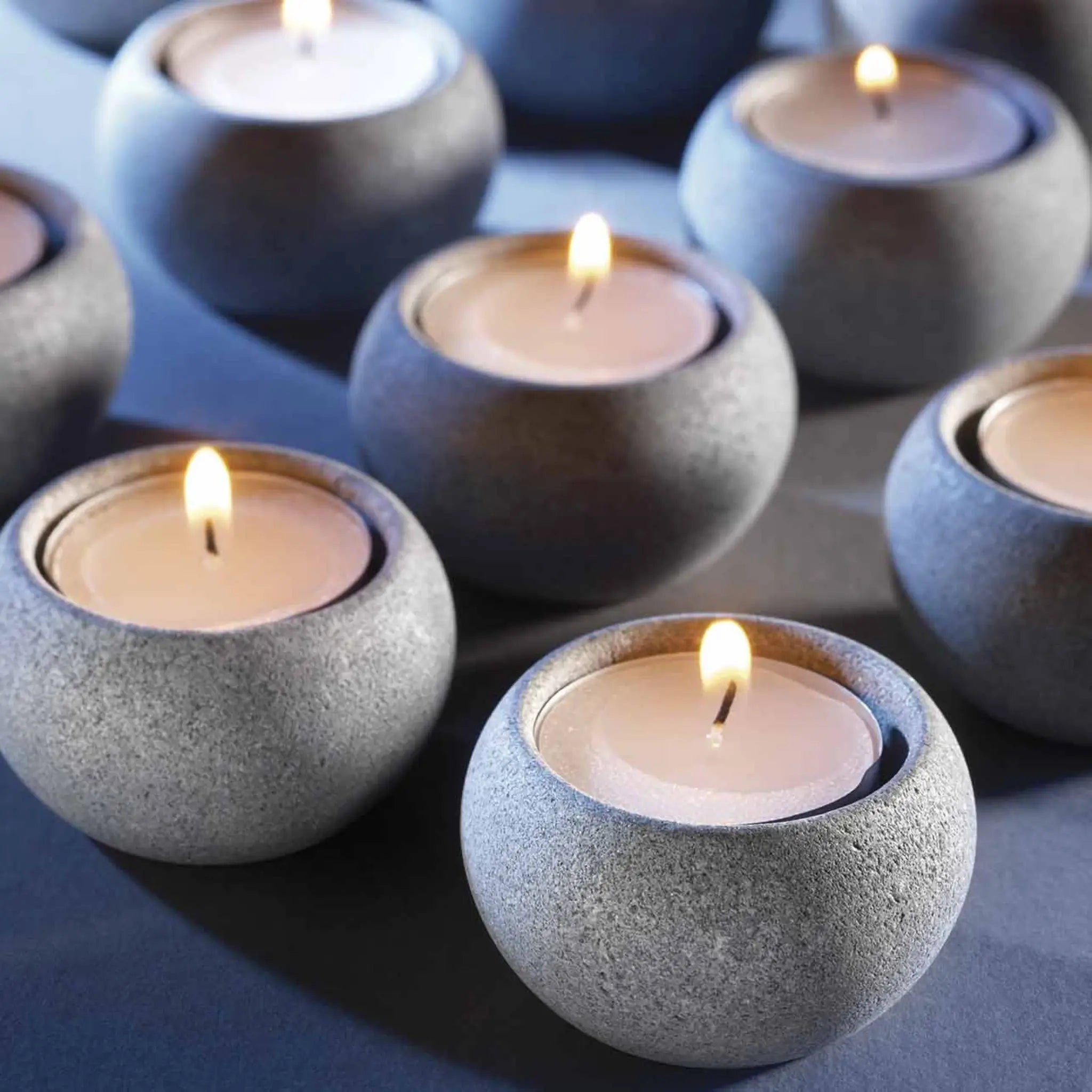Hukka soapstone tealight holders with lit candles arranged on a dark surface for a calm sauna atmosphere