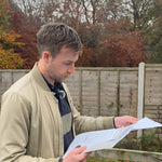 Glamping land acquisition specialist reviewing site plans on location as part of a glamping land acquisition and site shortlisting report