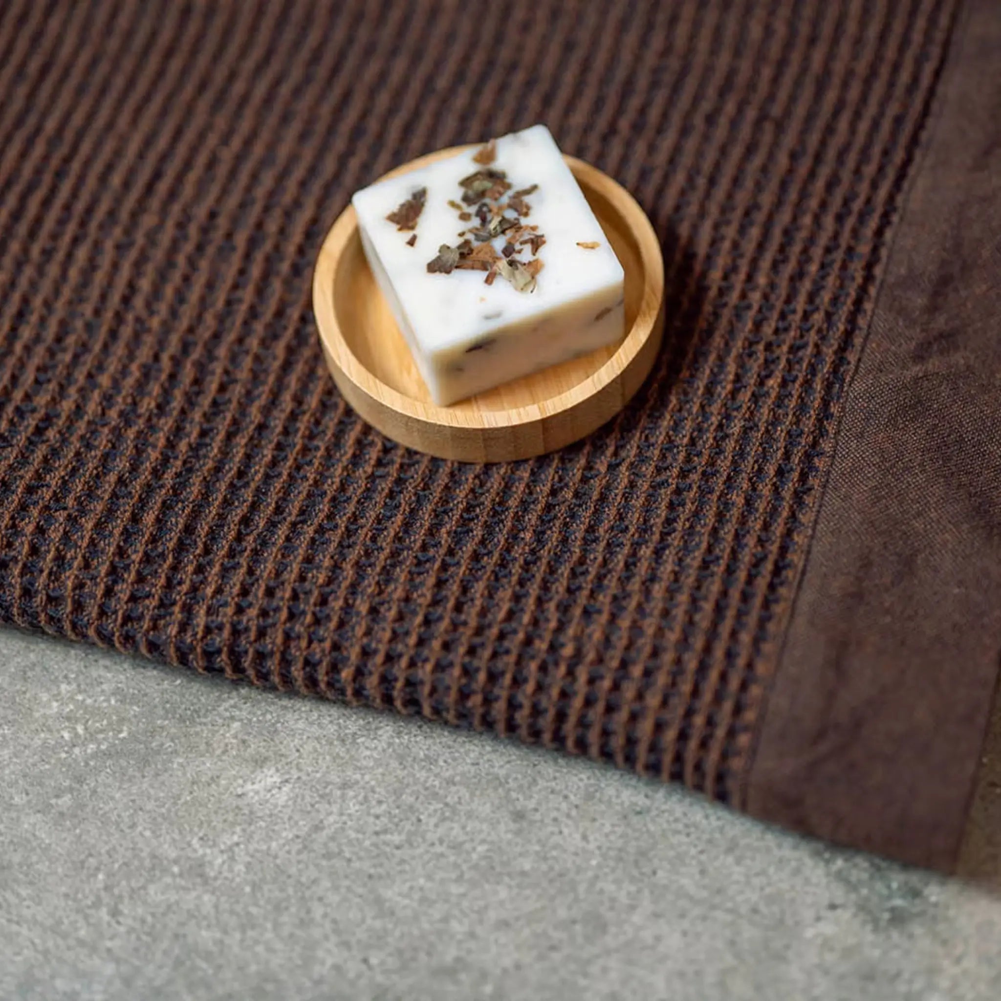 Rento Birch Soap 50g displayed on a wooden soap dish beside a brown sauna seat cover.