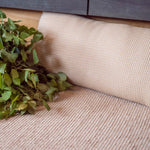 Beige Rento Kenno sauna pillow and matching seat cover with birch branches on a wooden sauna bench
