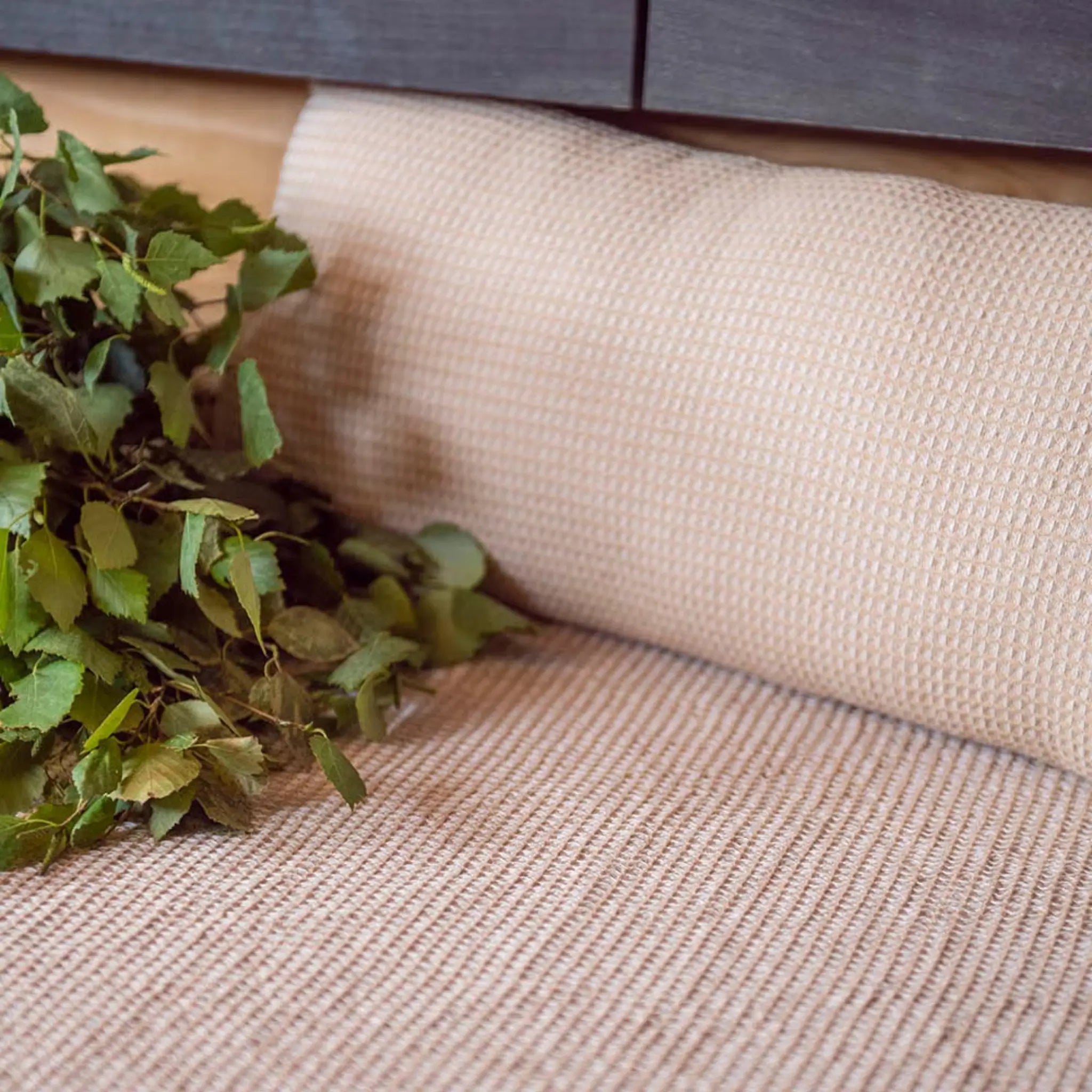 Beige Rento Kenno sauna pillow and matching seat cover with birch branches on a wooden sauna bench