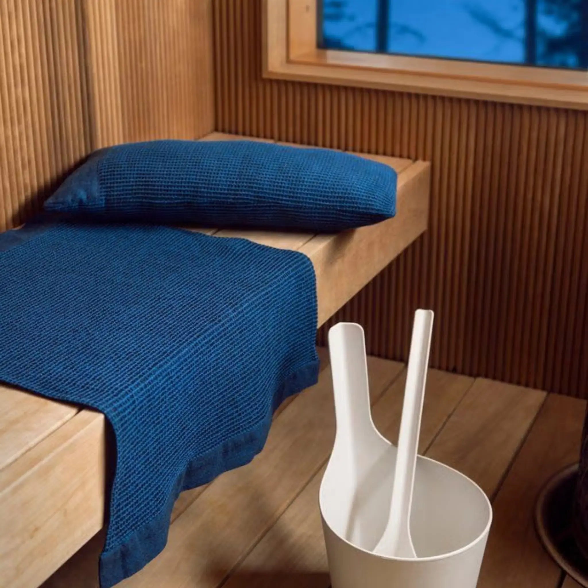 Dark blue Rento Kenno sauna pillow and matching seat cover styled inside a sauna room with sauna bucket