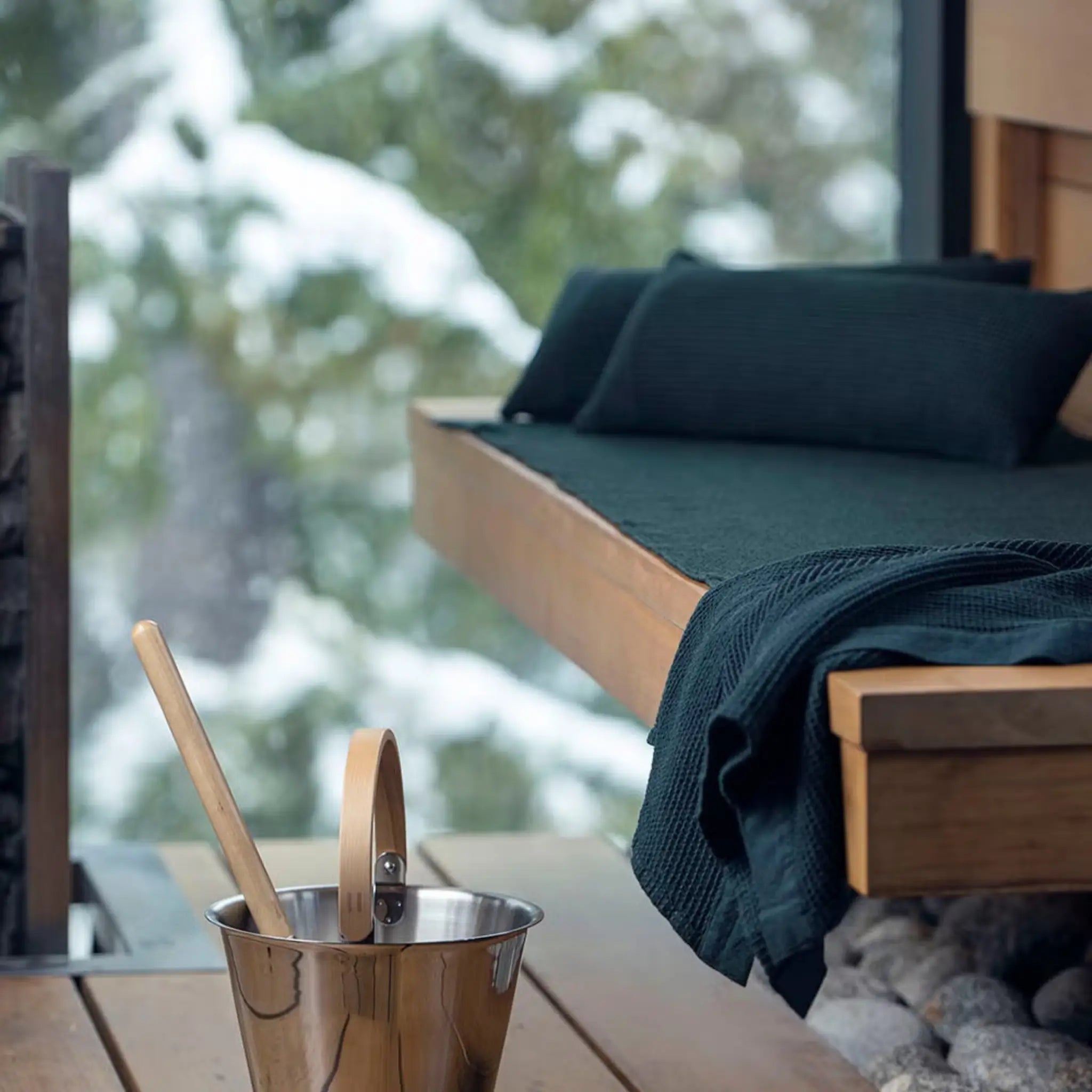 Dark green Rento Kenno sauna pillow and matching sauna textiles styled on a wooden sauna bench