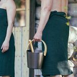 Close-up of dark green waist towel worn after sauna with textured fabric and sauna bucket detail