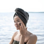Woman applying natural Finnish peat mask during outdoor sauna wellness ritual