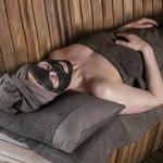 Woman relaxing in sauna with nourishing Finnish peat facial mask treatment