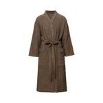 Adult wearing a brown Rento Kenno bathrobe outside a steaming sauna cabin