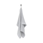 Grey and white Rento Kenno hand towels stacked on a wooden bench in a sauna setting.