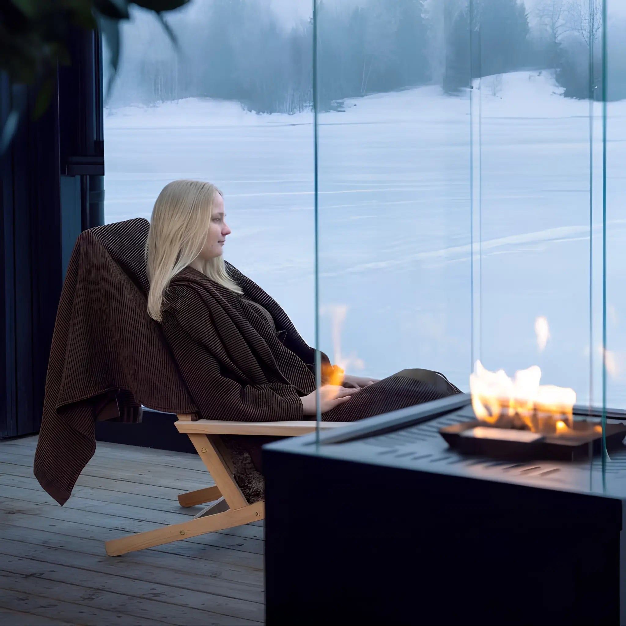 Dark brown waffle texture bath towel draped over a lounge chair beside a glass fireplace and snowy view