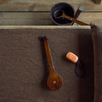 Dark brown Rento Kenno sauna seat cover on a bench with wooden ladle and bar soap
