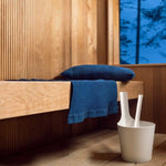 Dark blue Rento Kenno sauna pillow and matching seat cover styled on a wooden sauna bench