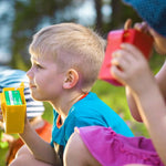 Children using colourful Mehujehu juice box holders outdoors