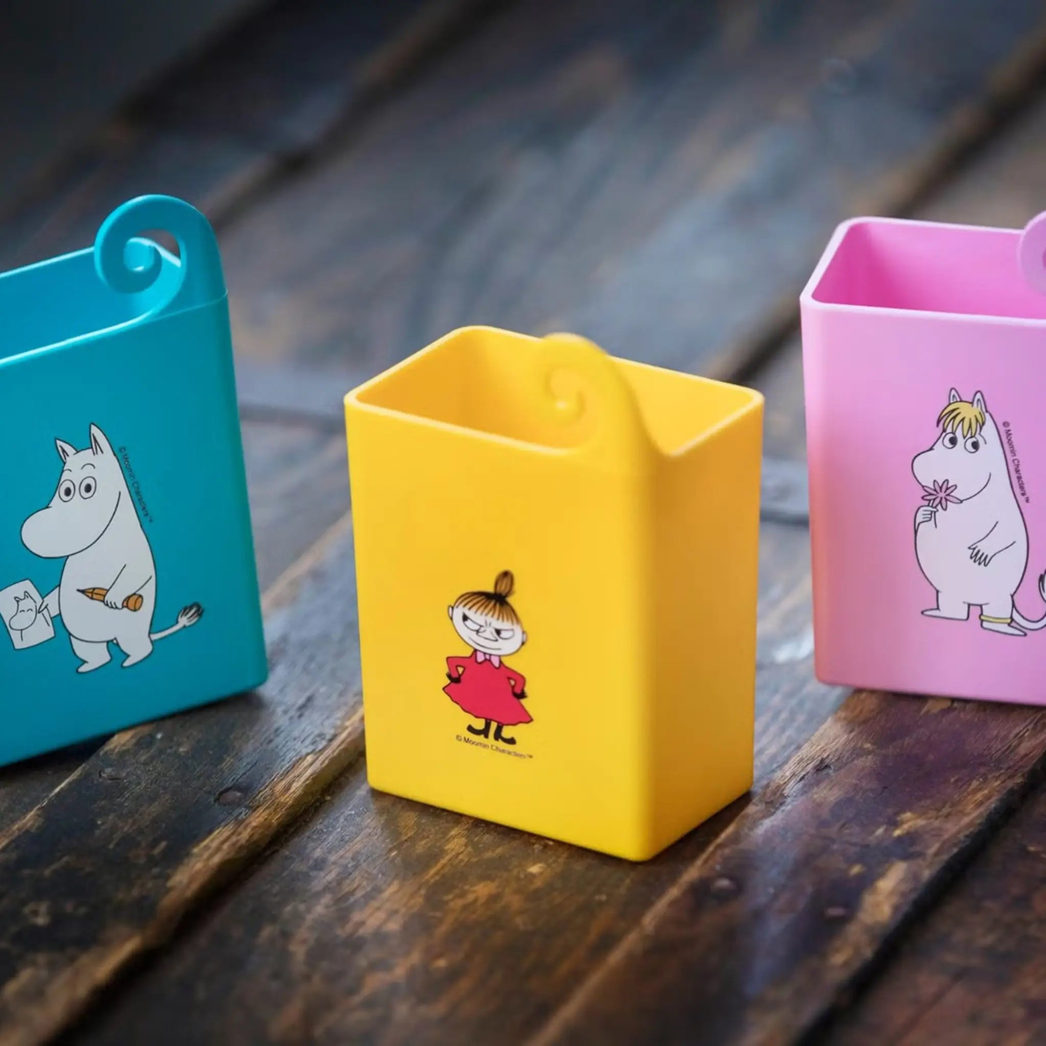 Colourful Mehujehu juice box holders with Moomin character designs on wooden surface