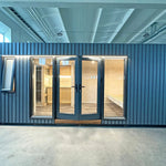 The Large GlampTainer container-style glamping unit – full frontal view with black vertical slat cladding, expansive glazing and bright interior