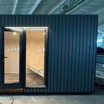 The Large GlampTainer container-style glamping unit – front view showcasing black vertical cladding, wide glass doors, and warm wooden interior