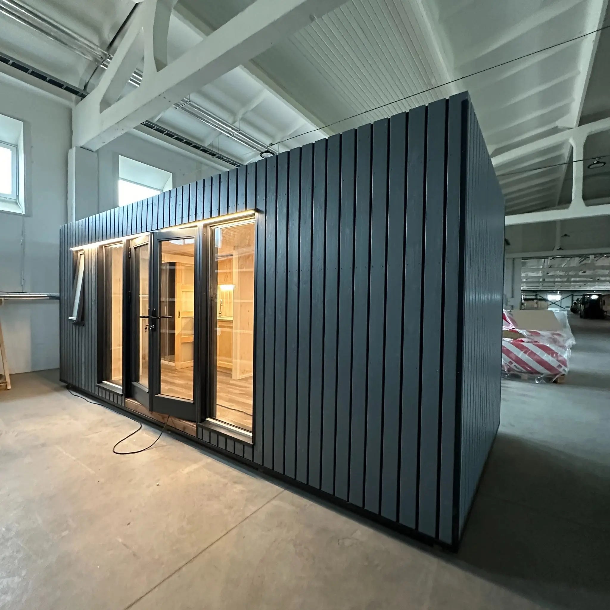 The Large GlampTainer container-style glamping unit – angled view from right side showing contemporary black cladding and full-height windows