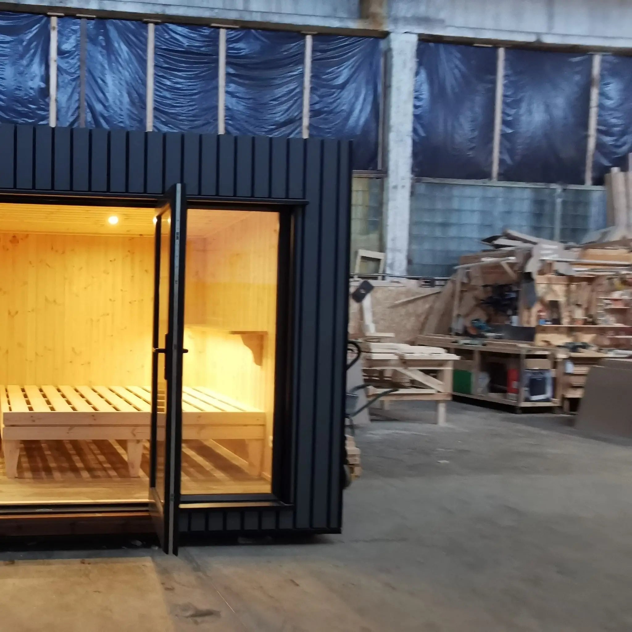 The Medium GlampTainer container-style glamping structure – right side front view with glass door open, showing bed frame and timber interior panelling.