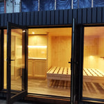The Medium GlampTainer container-style glamping structure – view from entrance showing timber-lined bedroom with bed frame and warm ambient lighting.