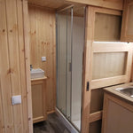 The Medium GlampTainer container-style glamping structure – kitchen sink beside sliding door leading to bathroom area with modern fittings.