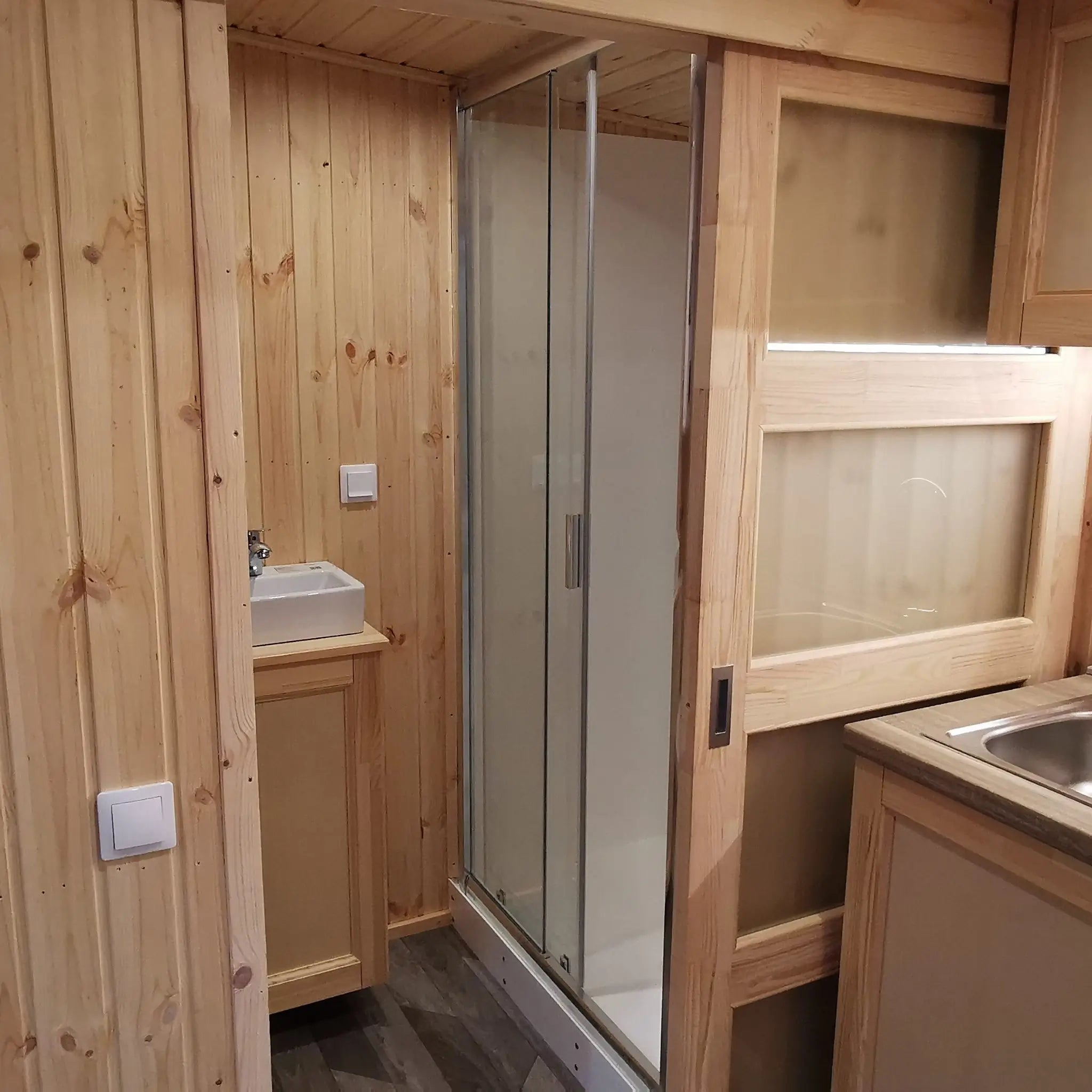 The Medium GlampTainer container-style glamping structure – kitchen sink beside sliding door leading to bathroom area with modern fittings.