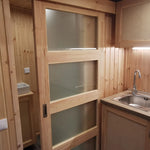 The Medium GlampTainer container-style glamping structure – interior view showing kitchenette, sliding door, and shower bathroom.