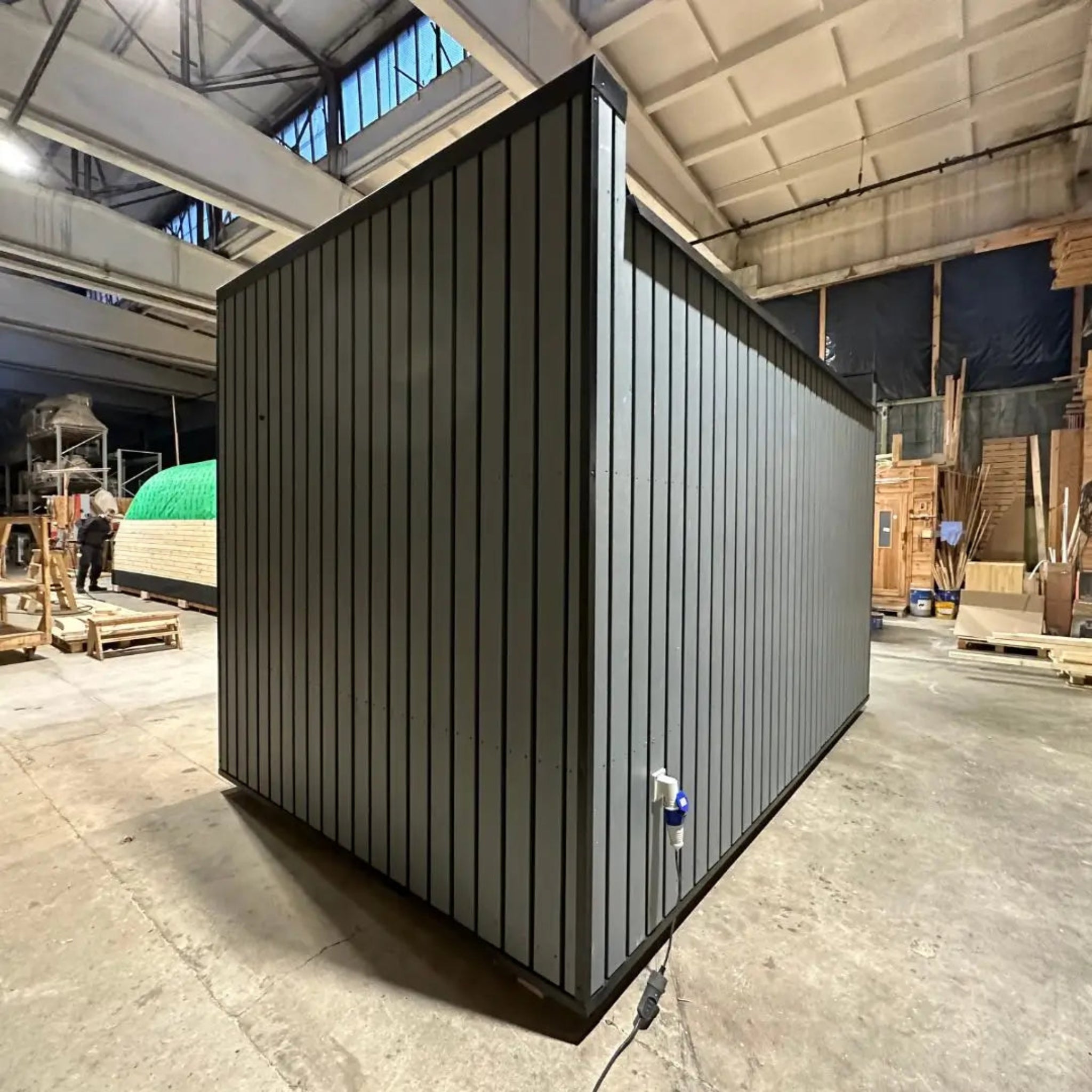 The Small GlampTainer container-style glamping structure – rear exterior view showcasing sleek vertical grey cladding and modern modular design.