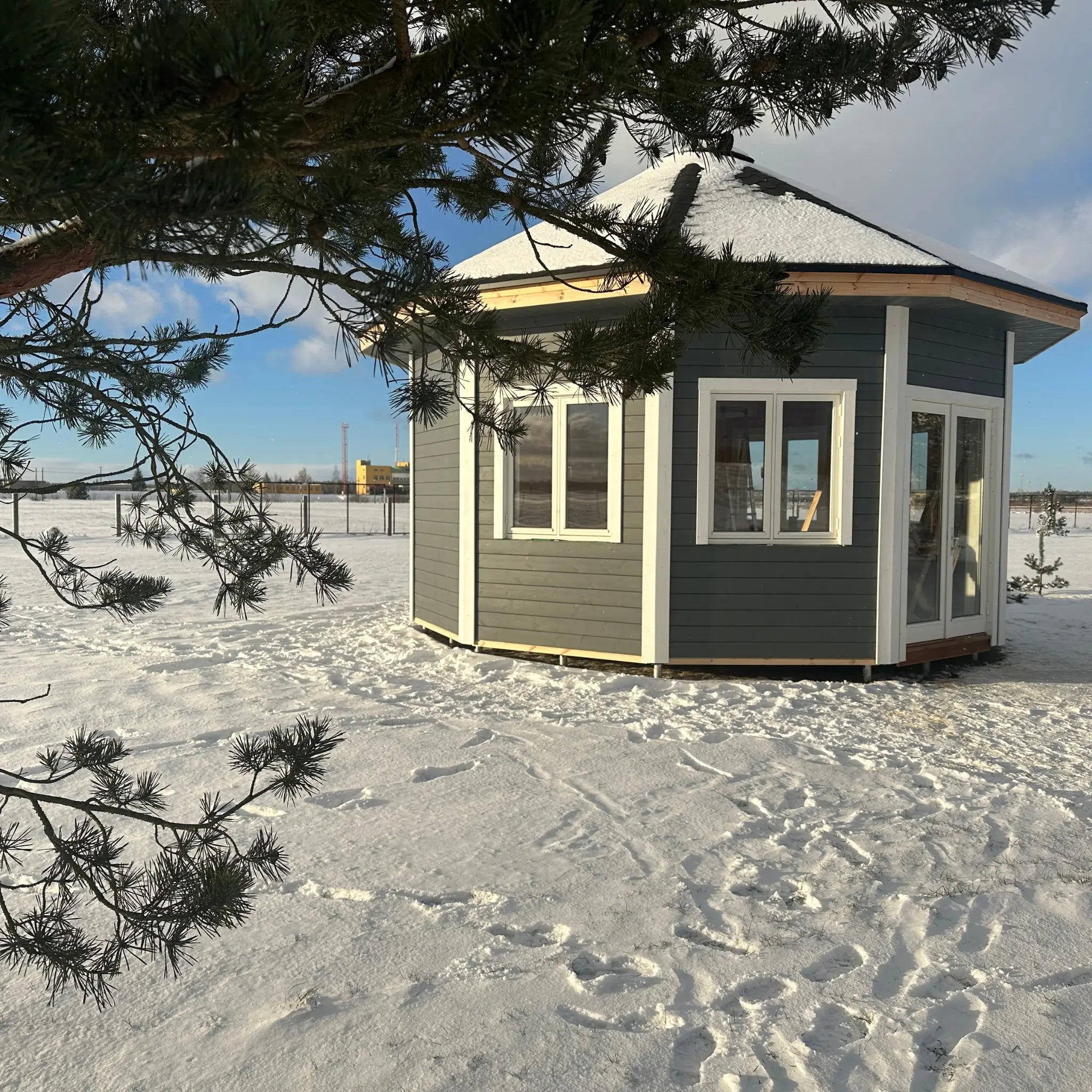 Angled side view of the Altura Loft Cabin in winter showing windows and roof overhang