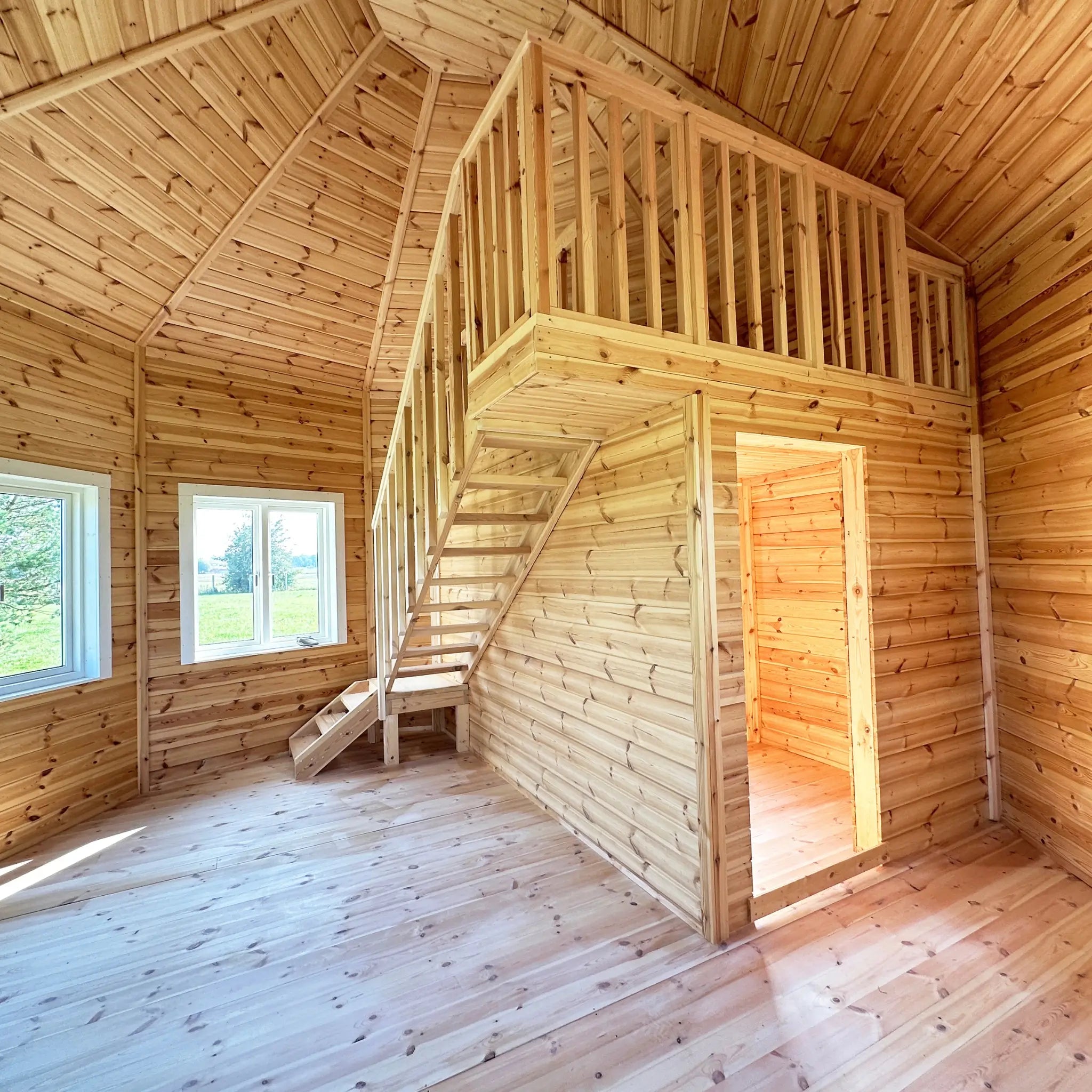 Open-plan living area with timber staircase leading to the loft in the Altura Loft Cabin