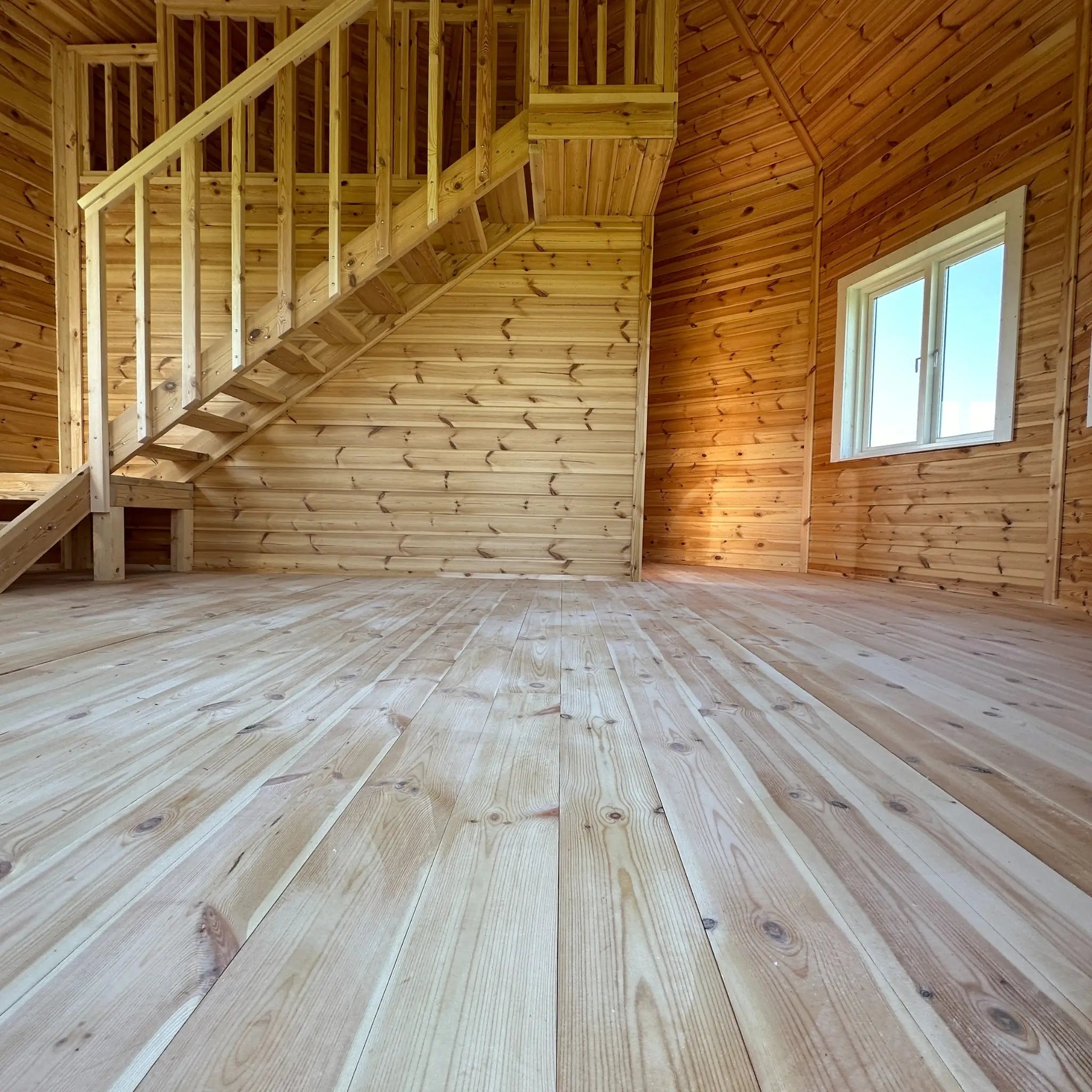 Wide-angle view of the open living space with timber flooring and staircase in the Altura Loft Cabin