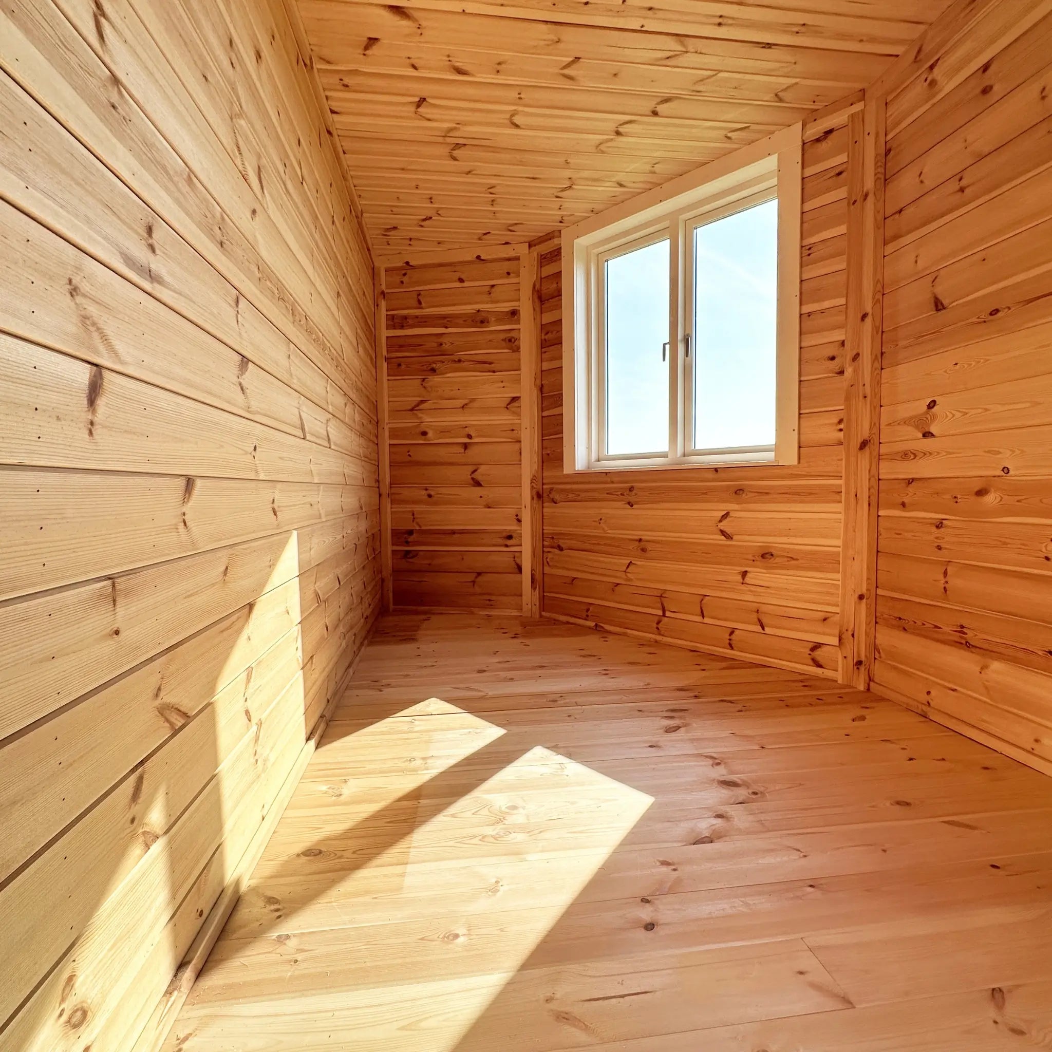 Interior view of the room beneath the loft showing timber wall panelling and natural light from window in the Altura Loft Cabin