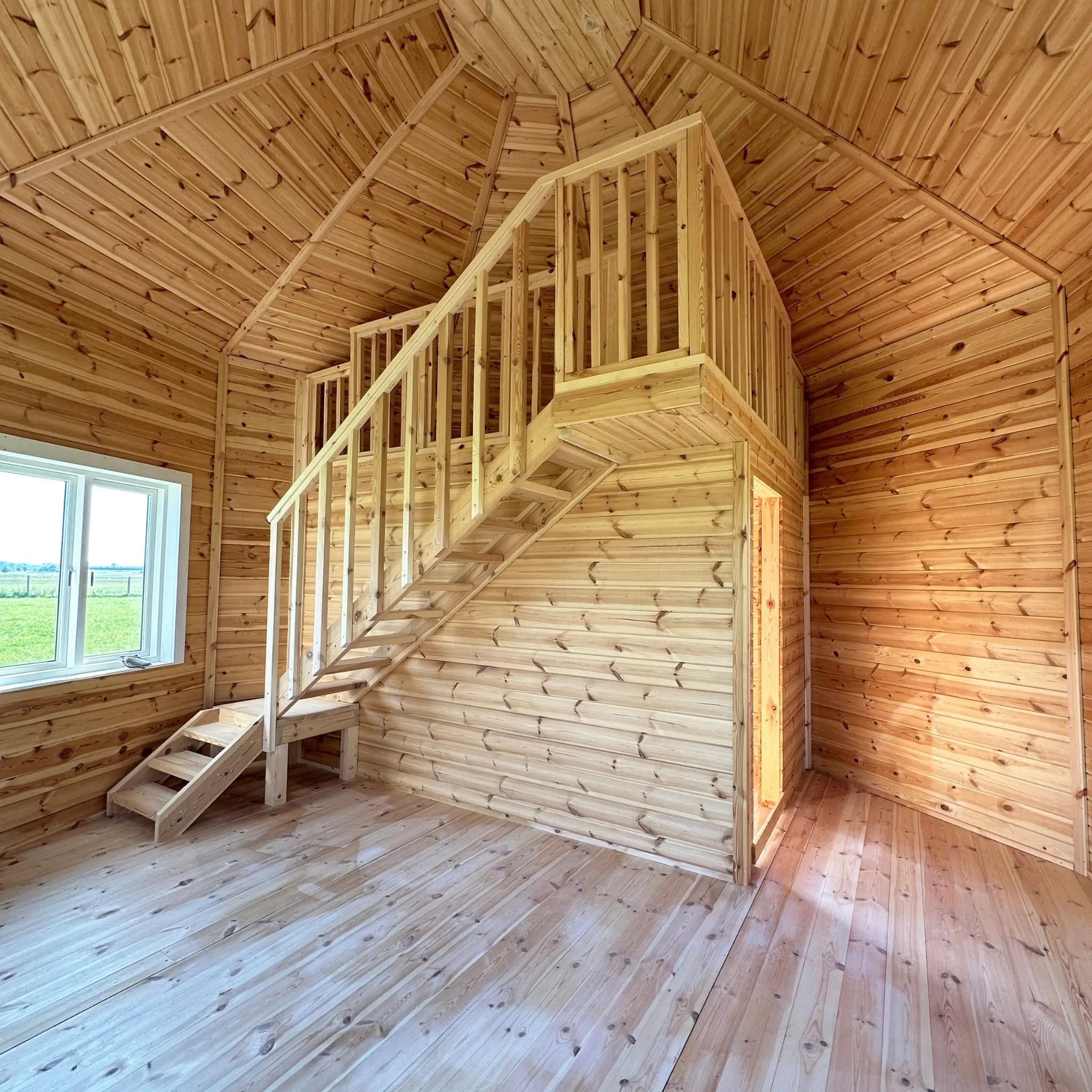Spacious living area with exposed timber walls, pitched ceiling, and multiple windows in the Altura Loft Cabin