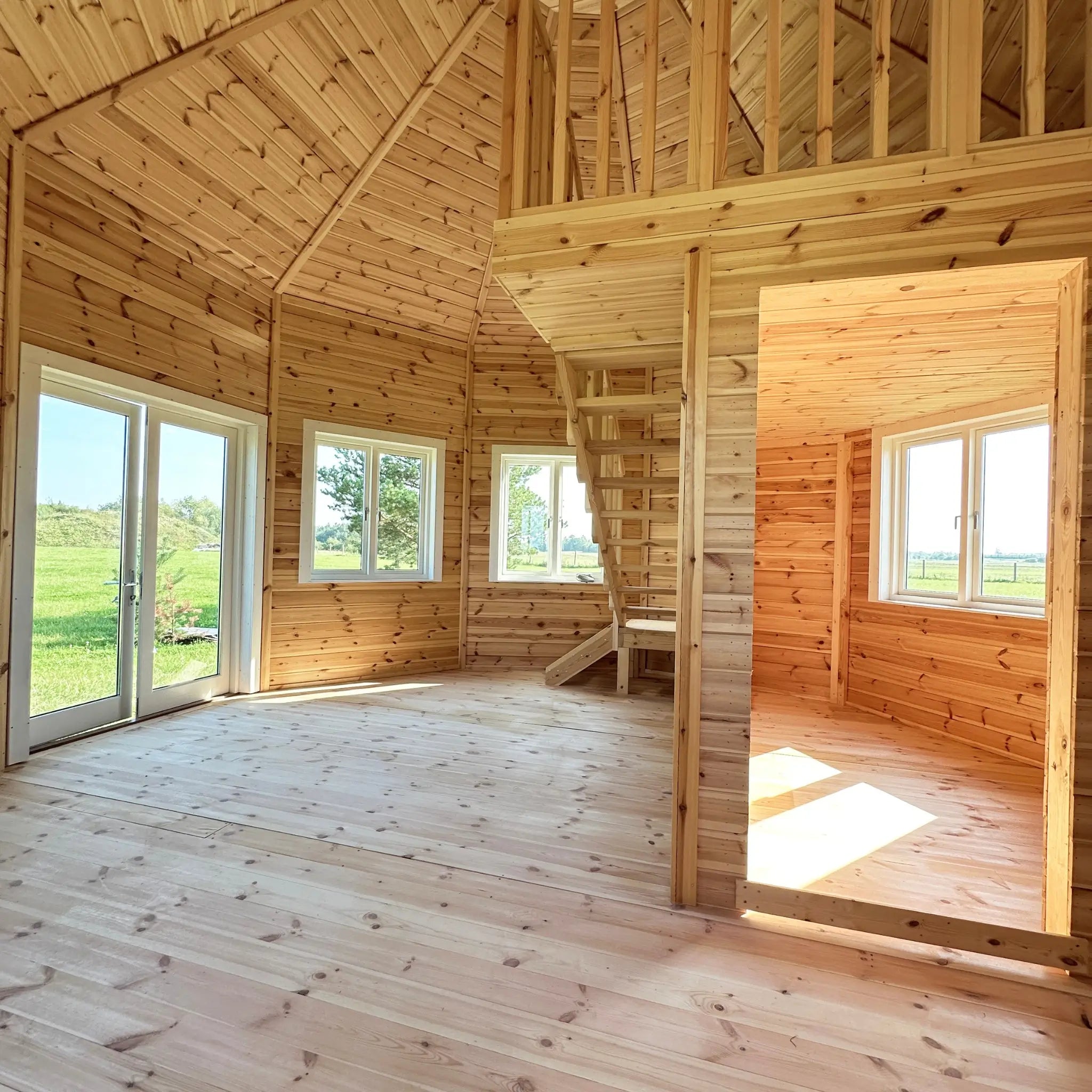 Open-plan living area with timber staircase leading to the loft in the Altura Loft Cabin