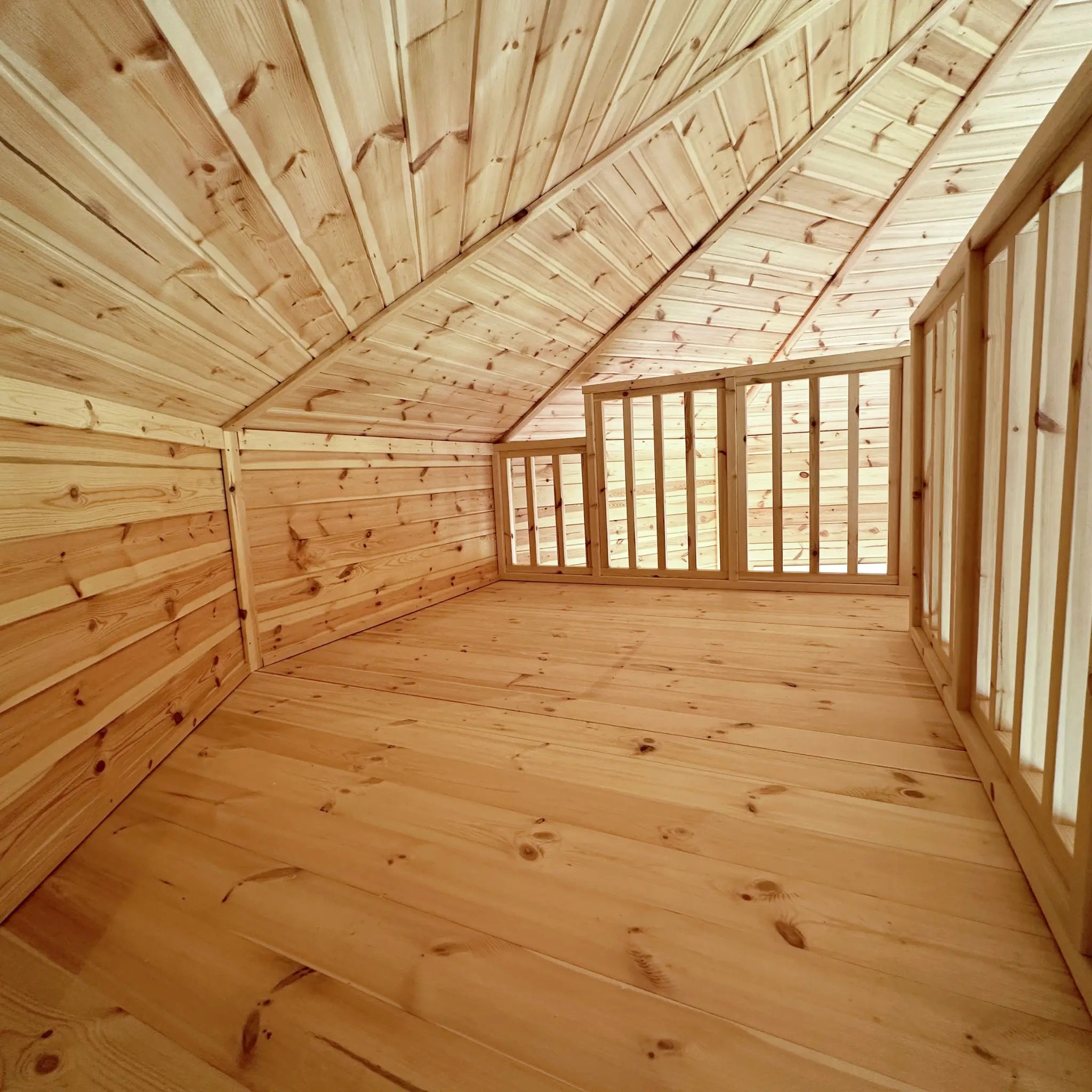 Loft sleeping area with timber floor, sloped ceiling, and safety balustrade in the Altura Loft Cabin