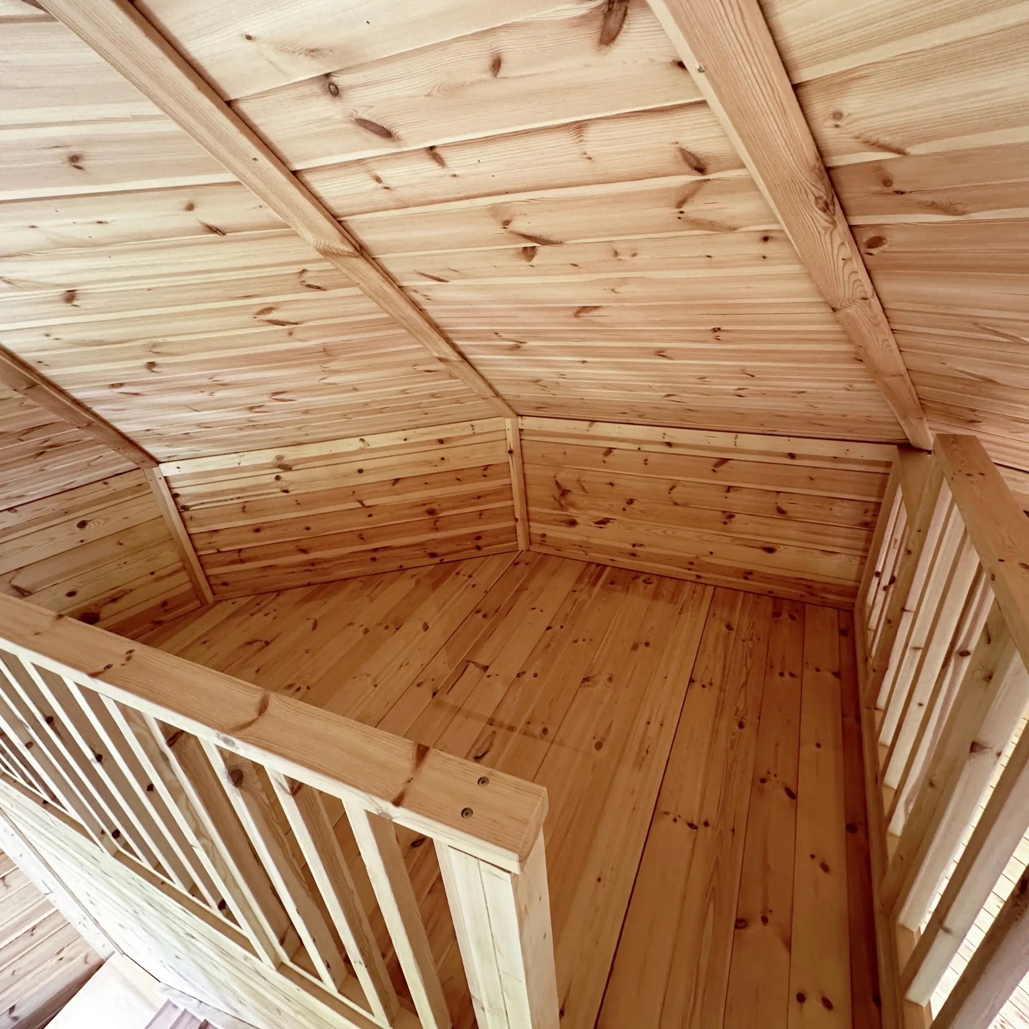 Upper loft platform with timber railing and pitched ceiling inside the Altura Loft Cabin