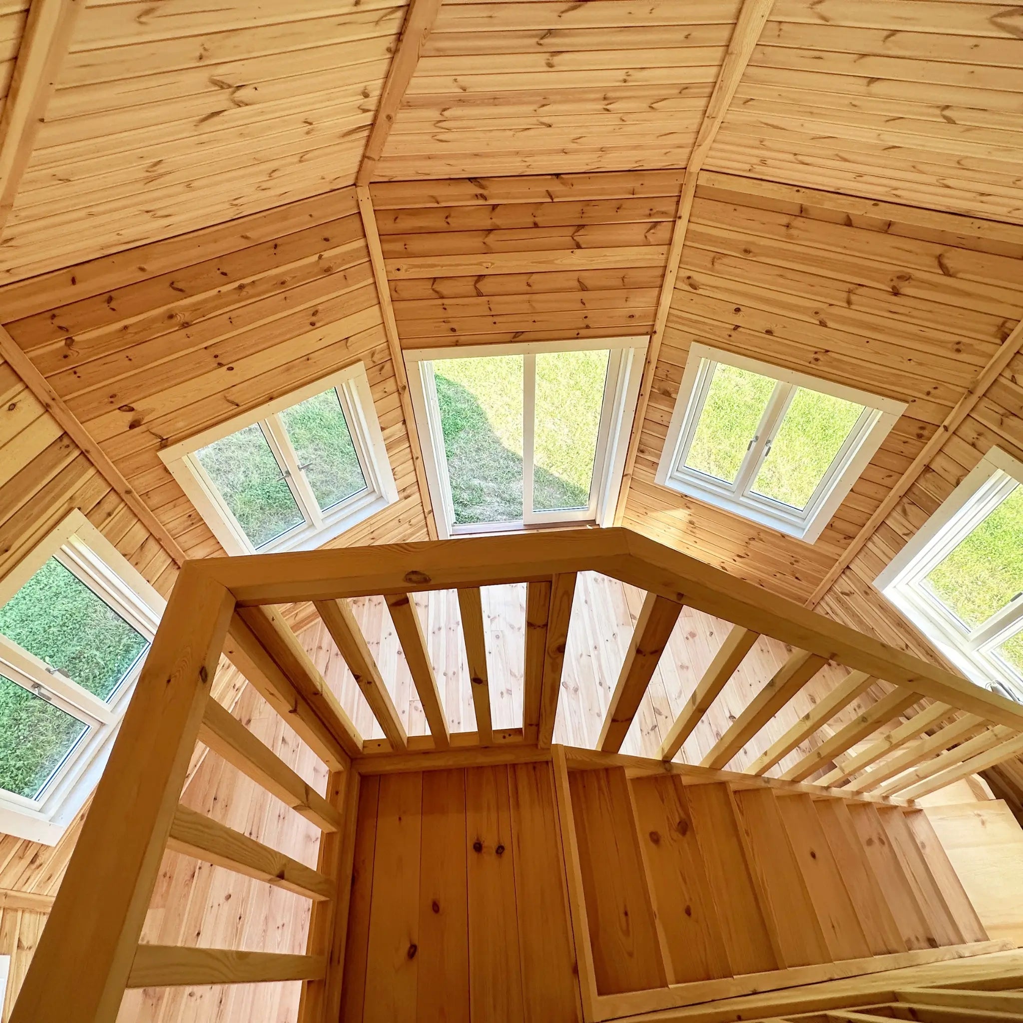 Top-down view from the loft showing staircase, balustrade, and window-lined walls below in the Altura Loft Cabin