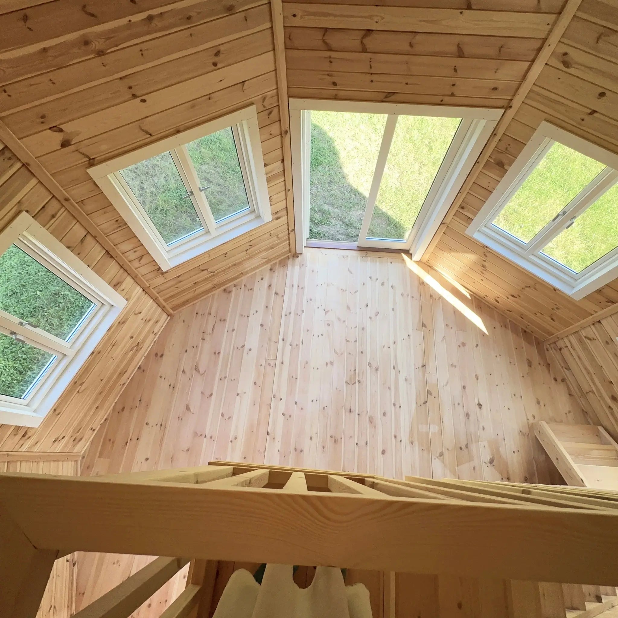 View from the loft level overlooking the Altura Loft Cabin ground floor with multiple angled windows